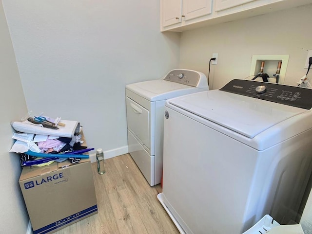 laundry area with cabinet space, light wood-style flooring, baseboards, and separate washer and dryer