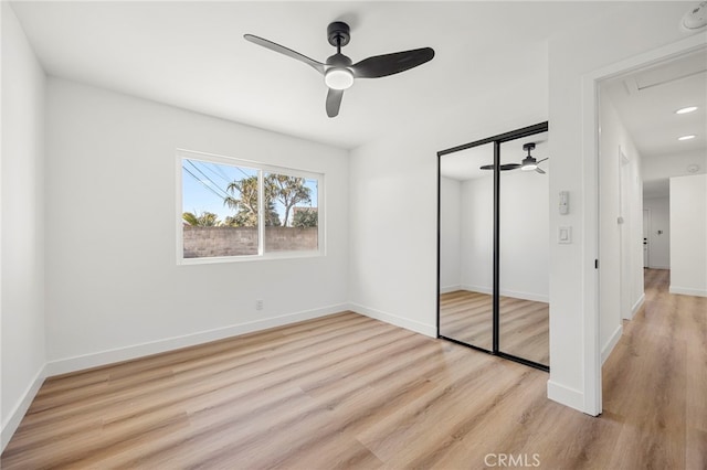 unfurnished bedroom featuring a closet, baseboards, wood finished floors, and a ceiling fan