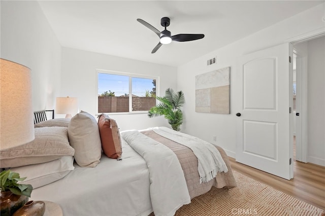 bedroom featuring light wood-style flooring, baseboards, visible vents, and ceiling fan