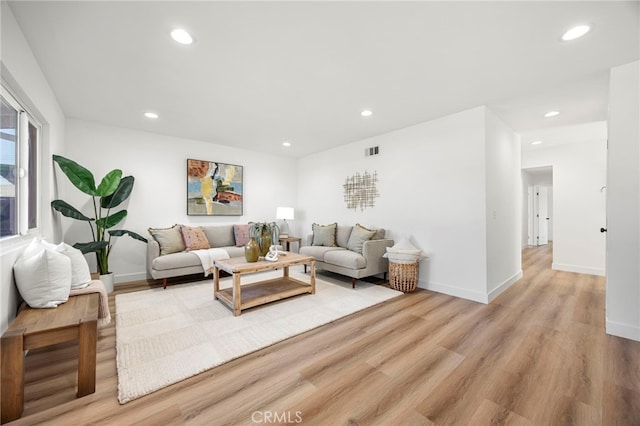 living room featuring recessed lighting, baseboards, and light wood-style floors