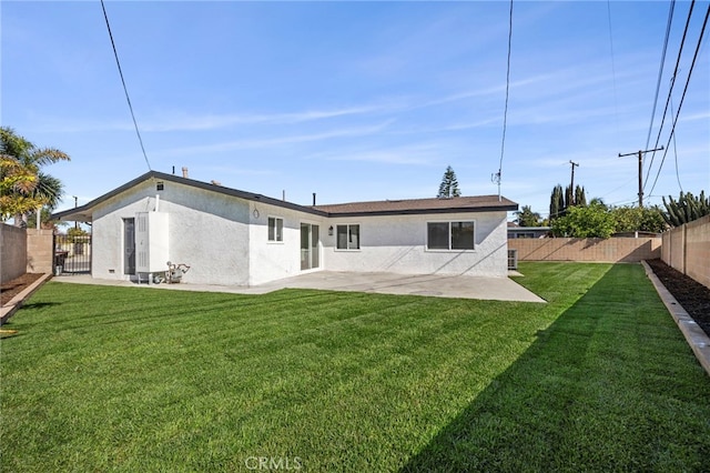 back of house with stucco siding, a lawn, and a fenced backyard