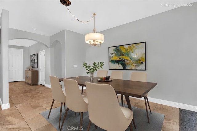 dining area featuring an inviting chandelier, baseboards, arched walkways, and marble finish floor