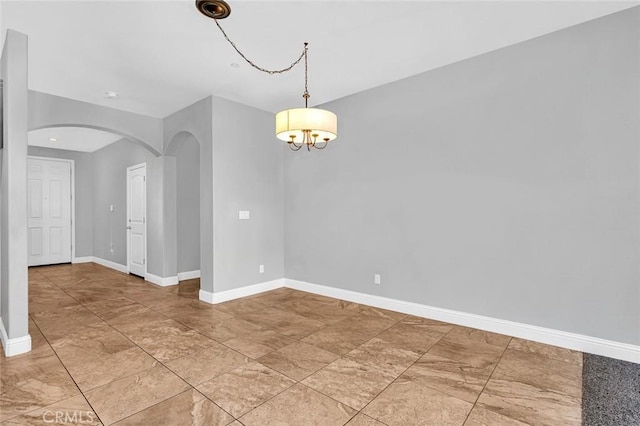 spare room with baseboards and arched walkways