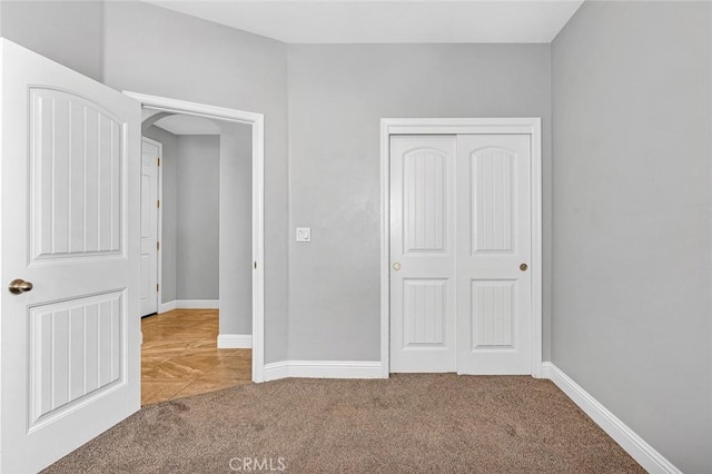 unfurnished bedroom featuring carpet flooring, baseboards, and a closet