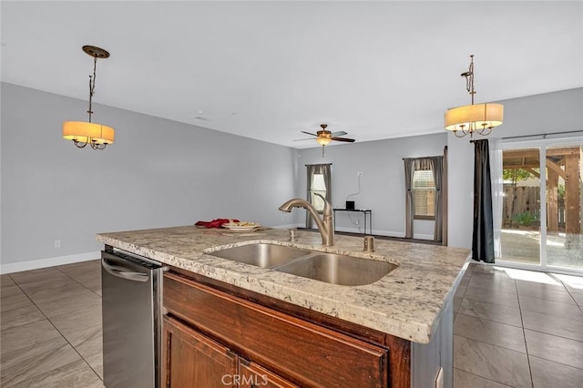 kitchen featuring a center island with sink, a sink, baseboards, dishwasher, and hanging light fixtures