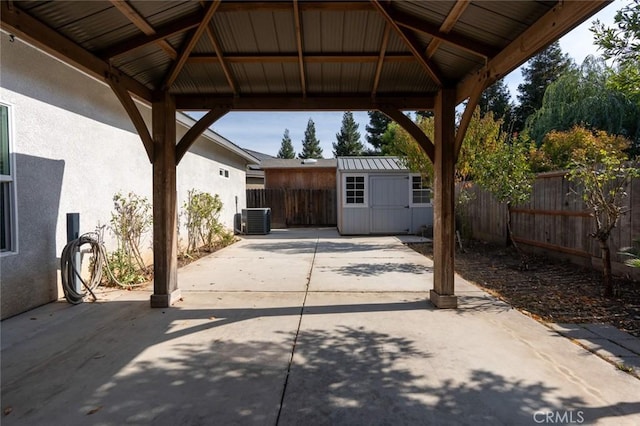 view of patio featuring a gazebo, an outdoor structure, a fenced backyard, and a shed