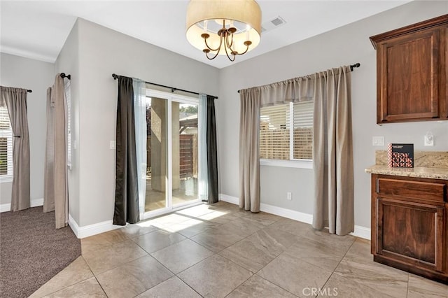 unfurnished dining area featuring visible vents, an inviting chandelier, and baseboards