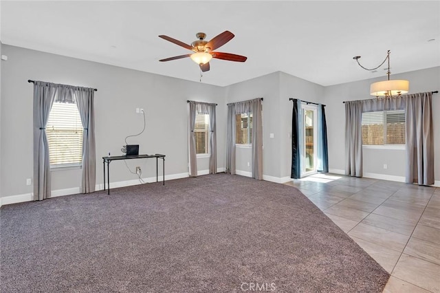 carpeted empty room featuring tile patterned floors, a ceiling fan, and baseboards