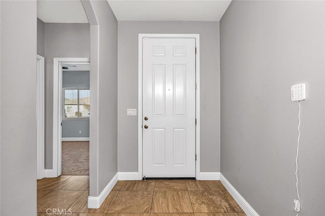 interior space with baseboards and arched walkways