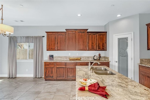 kitchen with decorative light fixtures, recessed lighting, light stone counters, and a sink