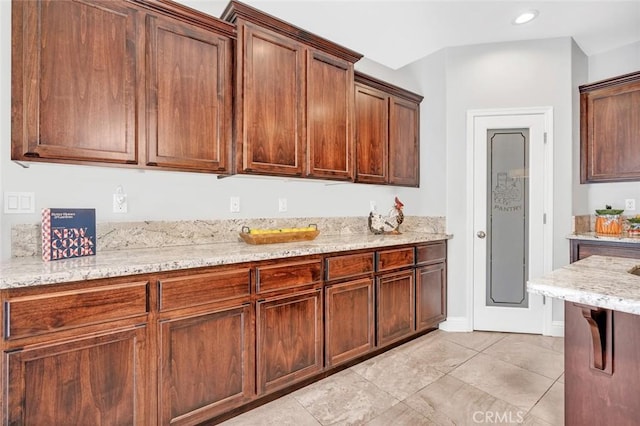 kitchen featuring light stone counters, light tile patterned floors, recessed lighting, and baseboards