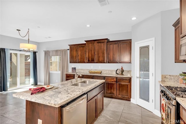 kitchen with light stone countertops, recessed lighting, a sink, appliances with stainless steel finishes, and pendant lighting