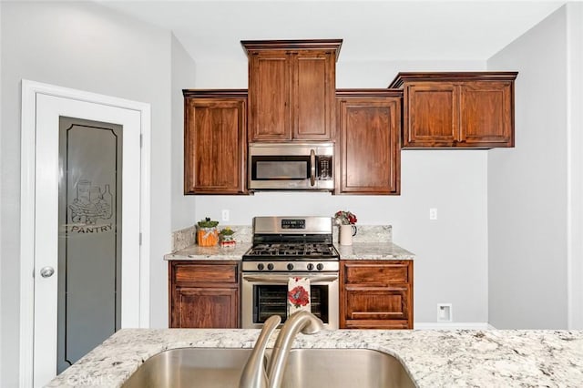 kitchen featuring light stone counters, appliances with stainless steel finishes, and a sink