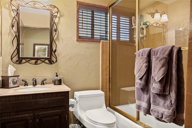 full bathroom with shower / bath combination with glass door, toilet, vanity, and a textured wall