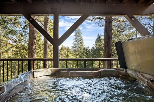 unfurnished sunroom featuring a jacuzzi and a wooded view