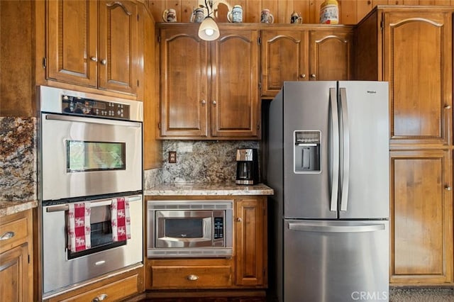 kitchen featuring backsplash, brown cabinets, appliances with stainless steel finishes, and light stone counters