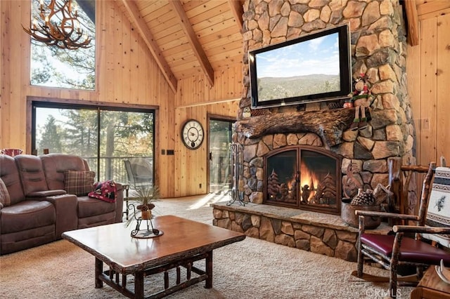 living area with wooden walls, beamed ceiling, wood ceiling, carpet floors, and a stone fireplace