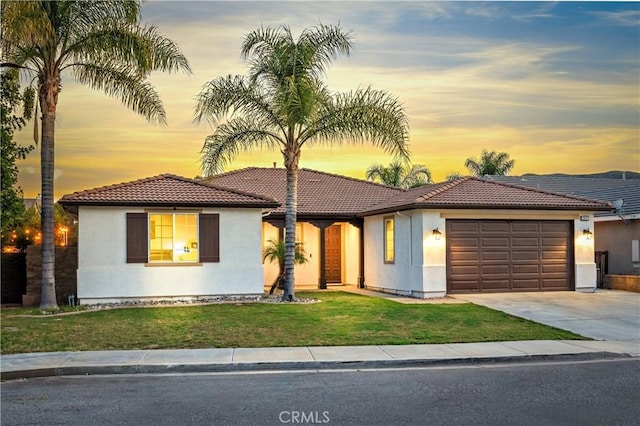 view of front of property featuring stucco siding, driveway, a tile roof, a front yard, and an attached garage