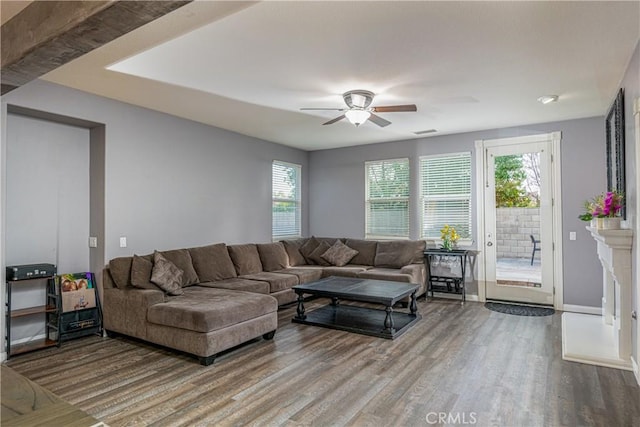 living room with ceiling fan, visible vents, baseboards, and wood finished floors