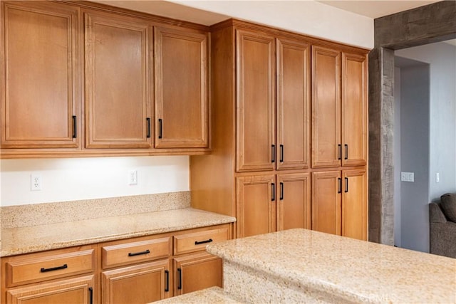 kitchen featuring light stone counters and brown cabinets