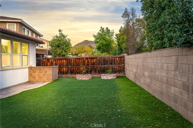 yard at dusk with a fenced backyard