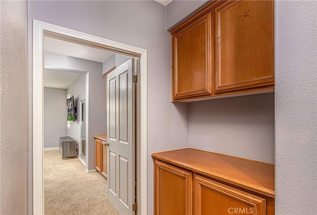 hallway featuring light carpet and baseboards