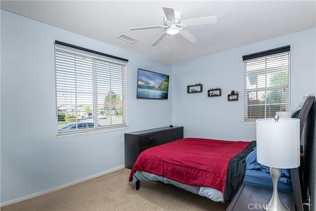 carpeted bedroom with visible vents, multiple windows, baseboards, and ceiling fan