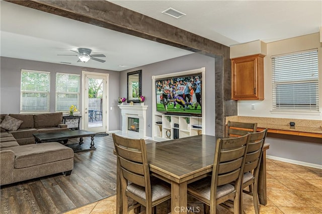 dining area featuring a ceiling fan, baseboards, visible vents, light wood-style flooring, and a glass covered fireplace