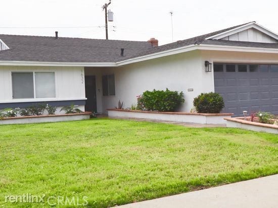 ranch-style home with a garage, roof with shingles, a front lawn, and stucco siding