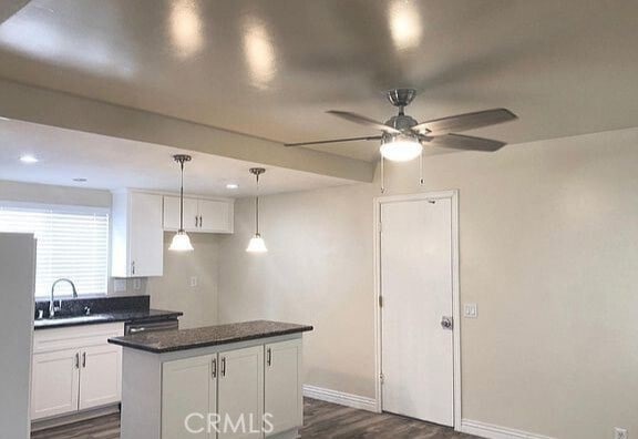 kitchen with a sink, dark countertops, freestanding refrigerator, white cabinets, and dark wood-style flooring