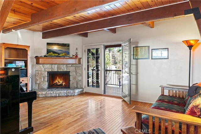 living room with beamed ceiling, wood ceiling, hardwood / wood-style floors, and a fireplace