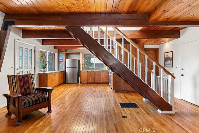 interior space with beamed ceiling, light wood-style flooring, wood ceiling, and stairs