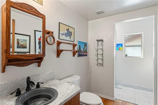 bathroom with visible vents, toilet, vanity, and baseboards