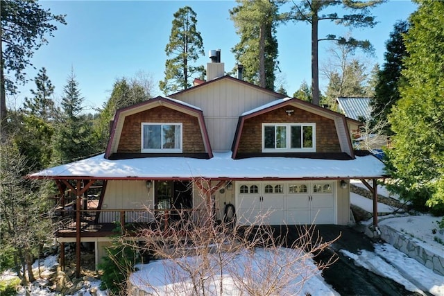 view of front of house with a gambrel roof, aphalt driveway, a garage, central AC unit, and a chimney