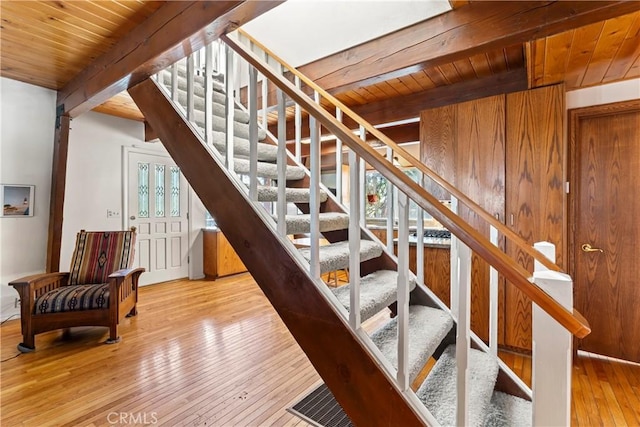 stairway with beam ceiling, a healthy amount of sunlight, and wooden ceiling