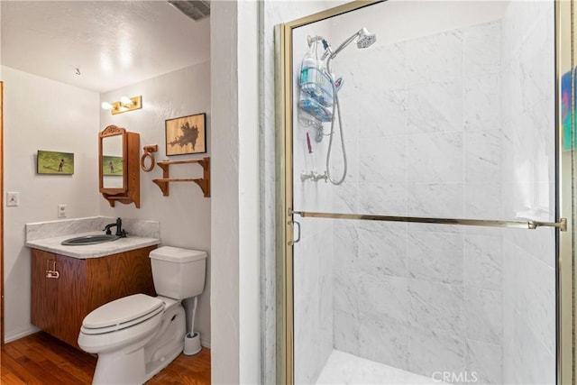 full bathroom featuring vanity, wood finished floors, visible vents, a shower stall, and toilet