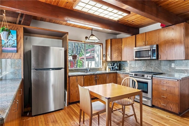 kitchen with brown cabinetry, backsplash, stainless steel appliances, and a sink