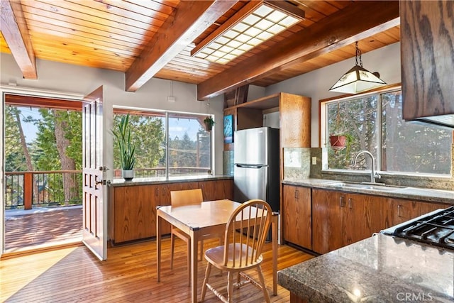 kitchen featuring light wood-style flooring, a sink, backsplash, freestanding refrigerator, and brown cabinetry