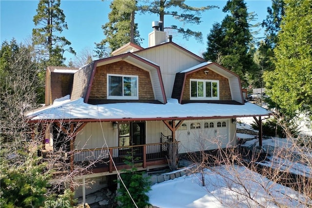 rear view of property featuring an attached garage, covered porch, a gambrel roof, and a chimney