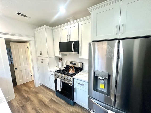 kitchen with visible vents, light stone counters, light wood-style floors, appliances with stainless steel finishes, and white cabinets