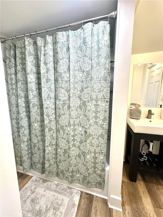 bathroom with wood finished floors, shower / bath combo, and a sink