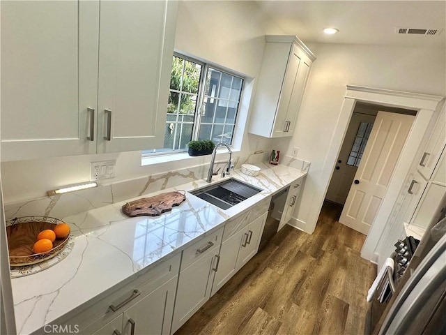 kitchen with visible vents, a sink, light stone countertops, dishwasher, and dark wood-style flooring