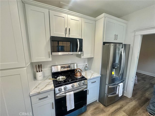 kitchen with appliances with stainless steel finishes, wood finished floors, and white cabinetry