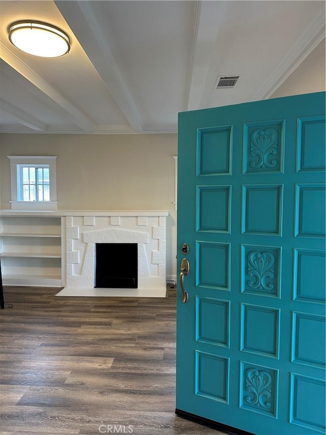 unfurnished living room with visible vents, a fireplace with flush hearth, beamed ceiling, and dark wood-style floors