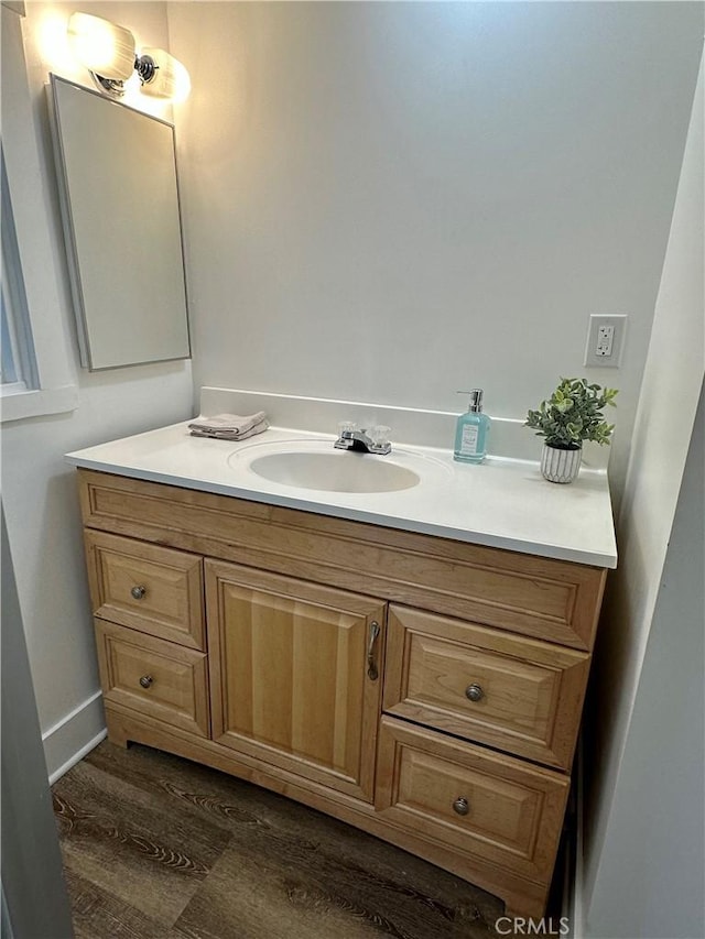 bathroom with baseboards, wood finished floors, and vanity