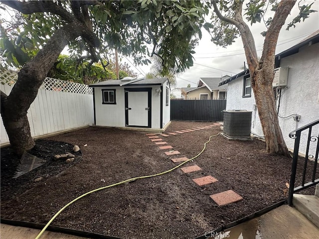 view of yard with an outdoor structure, a storage unit, central AC unit, and a fenced backyard