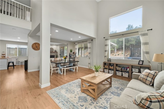 living room with a fireplace, wood finished floors, baseboards, and a towering ceiling