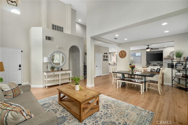 living room featuring wood finished floors, visible vents, baseboards, recessed lighting, and arched walkways