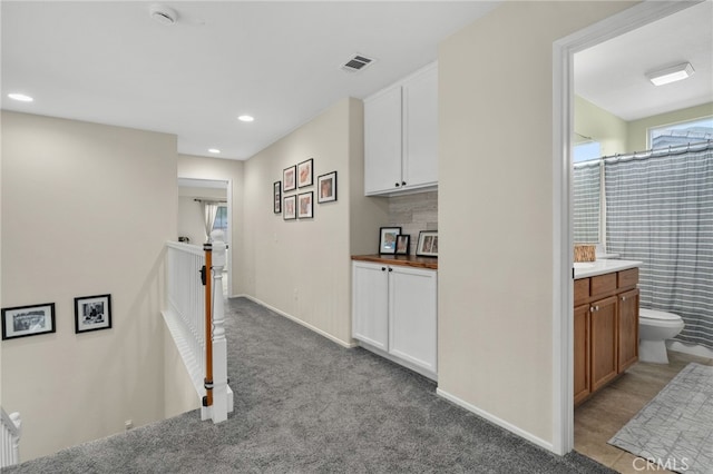 hallway with recessed lighting, baseboards, an upstairs landing, and carpet