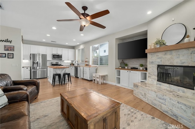 living area with recessed lighting, light wood-style flooring, a fireplace, and visible vents